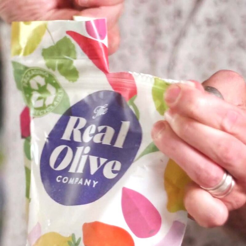 Someone peeling open one of the 1kg Real Olive Company resealable food bags.